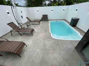 佩尼亚Casa de praia em Penha的一个带椅子和电视的庭院内的游泳池