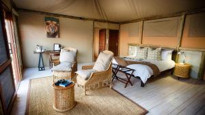 SavutiGhoha Hills Savuti Lodge的一间卧室,在帐篷里配有一张床和椅子