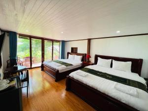 Chomka Thnong Resort的一间卧室配有两张床和一张桌子及一张书桌四柱床。