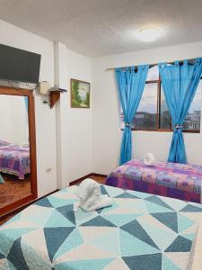 圣克里斯托瓦尔Moonlight, Galápagos的一间卧室配有两张带蓝色窗帘的床和电视。