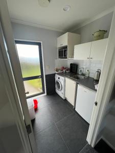 凯塔亚Taipa Views Bed & Breakfast的厨房配有白色橱柜、洗衣机和烘干机