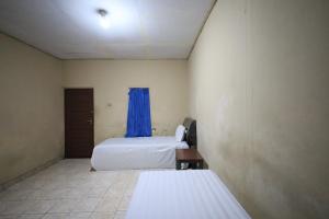 帕朗卡拉亚OYO 93343 Sukma Residence的一间设有两张床和蓝色窗帘的房间