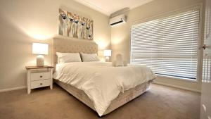 GriffinPerfect North Brisbane Retreat 4 bed的卧室设有一张白色大床和一扇窗户。