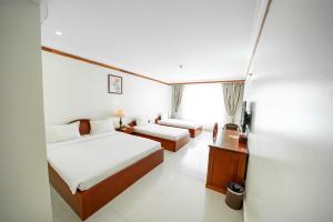 PursatPursat Riverside Hotel & Spa的酒店客房设有两张床和一张桌子。