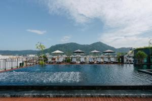 芭东海滩Rak Elegant Hotel Patong - SHA Extra Plus的一个带椅子和遮阳伞的大型游泳池