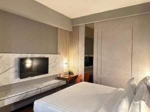 泗水d'primahotel Jemursari Surabaya的配有一张床和一台平面电视的酒店客房