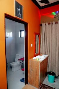 奇旺Hotel Park Treasure的橙色的浴室设有卫生间和镜子