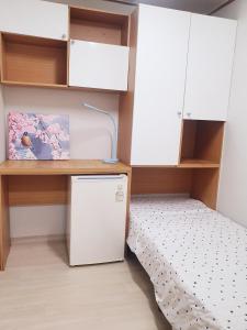 首尔Cony house的小房间设有一张床、一张桌子和橱柜