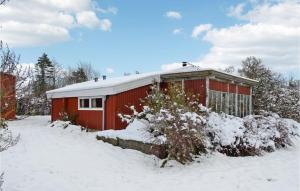 Bogø By3 Bedroom Nice Home In Bog By的一座红色的建筑,地面上积雪
