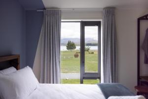 特卡波湖Haka House Lake Tekapo的一间卧室设有一张床和一个享有田野美景的窗户。