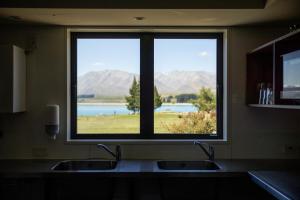 特卡波湖Haka House Lake Tekapo的享有湖泊和山脉美景的厨房窗户