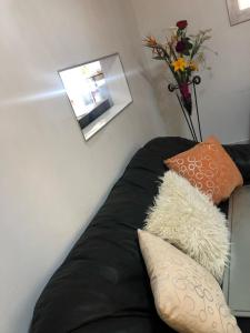 索韦托MajaK Guesthouse的一张带枕头的黑色沙发以及花瓶