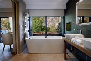 鲍内斯温德米尔英湖斯托尔斯大厅酒店的大型浴室设有两个盥洗盆和浴缸。