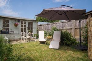 本布里奇Fern Cottage的庭院配有遮阳伞、椅子和桌子。