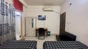 达卡Appayan Guest House Baridhara (Bhagyakula Building)的客房设有两张床、一张桌子和一台电视。