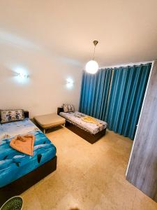 赫尔格达New Marina Hurghada Suite的一间卧室设有两张床,窗户配有蓝色窗帘