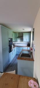 邓弗里斯The Wee Hoose的厨房配有蓝色橱柜、水槽和木桌。