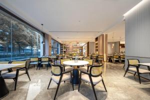 上海上海虹桥莘庄商务区亚朵酒店的餐厅设有桌椅和大窗户。