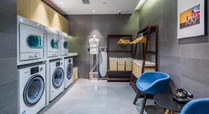 青岛青岛山东路中央商务区亚朵轻居酒店的洗衣房配有洗衣机和蓝色椅子