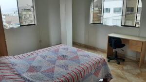 利马Terraza más habitaciones en La Molina的卧室配有一张床、一张书桌和窗户。
