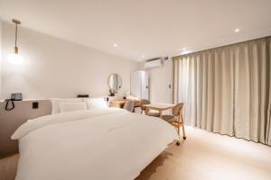 龟尾HOTEL SOHA的白色卧室配有一张大床和一张桌子