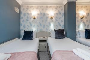 基尔肯尼The Waterfront Townhouse Accommodation的配有两张蓝色和白色壁纸的床铺