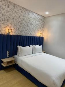 卡萨布兰卡Maarif Elite Suites的一间卧室配有一张大床和蓝色床头板