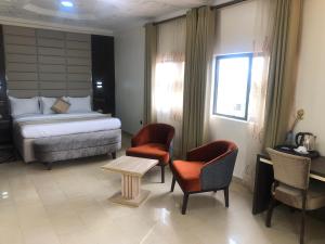 阿奴古Roban Hotels Limited的一间卧室配有一张床、两把椅子和一张桌子