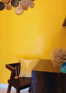 西达普尔Riyavar Luxury Homestay的一张木凳,配有桌子和黄色的墙壁