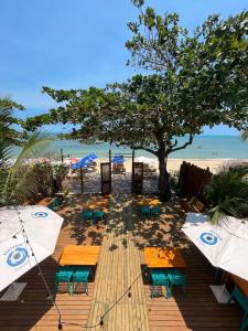 阿拉亚尔达茹达Santorini Beach Hotel的海滩上摆放着桌子和遮阳伞,还有一棵树