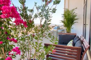 安曼丽湾酒店的阳台的一张长沙发,上面摆放着粉红色的鲜花