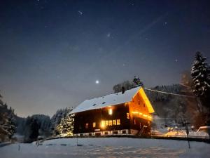 施卢赫湖Sporthostel Rössle的夜间雪中的一个灯火通明的小屋