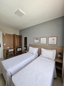 劳鲁-迪弗雷塔斯Aero Hotel的配有白色床单的酒店客房内的两张床