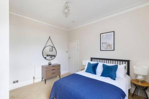 伦敦Tranquil 2BR Fulham Gem with Terrace Near Shops的一间卧室配有蓝色的床和镜子