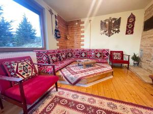 泰托沃Villa 80 Kodra e Diellit的客厅配有红色的沙发和两把椅子
