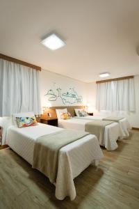阿雷格里港加里波第商务酒店的酒店客房,配有4张带白色床单的床