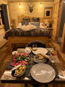 Les Écrins du Val de Mouthe, JURA的一张桌子,上面有食物和饮料,一张床