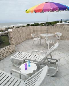 巴拉那州蓬塔尔Apartamento de cobertura na beira mar e de frente para o mar. Vista maravilhosa.的一个带桌椅和遮阳伞的庭院