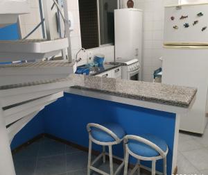 巴拉那州蓬塔尔Apartamento de cobertura na beira mar e de frente para o mar. Vista maravilhosa.的厨房配有蓝色的柜台和2把椅子