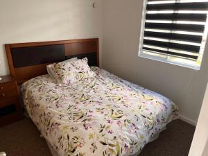 奥索尔诺Casa a 10 minutos del centro Osorno的一间卧室配有一张带花卉棉被的床和窗户。