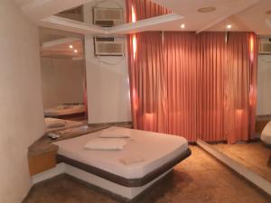 里约热内卢Jumbo Hotel (Adults Only)的一间卧室配有床、窗帘和镜子
