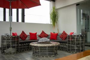 ZitácuaroHOTEL DEL CARMEN的客房设有一张带红色枕头的沙发和一张桌子。