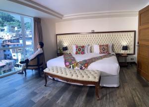 马丘比丘Jaya Machu Picchu Boutique Hotel的一间卧室配有一张大床,另一位女士坐在椅子上