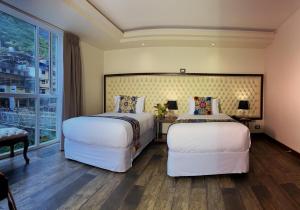 马丘比丘Jaya Machu Picchu Boutique Hotel的带大窗户的客房内的两张床