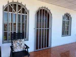 马那瓜Casa Robles - Your Stay Near Airport的带三扇窗户的房间里一张黑椅子