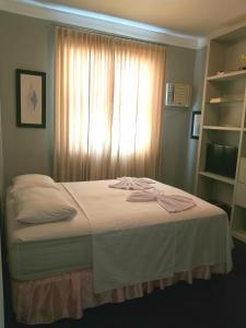 萨尔瓦多Erva Cidreira Hostel的一间卧室配有一张带白色床单的床和一扇窗户。