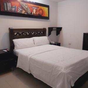 巴耶杜帕尔HOTEL SARACHUY VALLEDUPAR的一间卧室配有一张带白色床单的大床