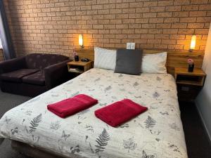 吉尔甘德拉三种方式汽车旅馆的一间卧室配有一张带两个红色枕头的床