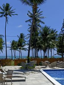 塔曼达雷Beira-mar Tamandaré / Carneiros的一个带椅子和棕榈树的游泳池以及大海