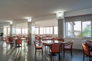 陶尔米纳科拉罗酒店的用餐室设有桌椅和窗户。